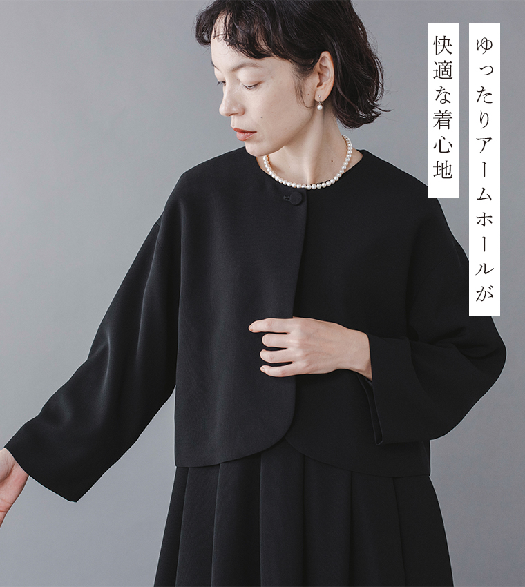 Luuna miu【慶弔両用】大切な日のジャケット＆ワンピースセットのディテールイメージ。黒のノーカラージャケットを着たモデルが腕を軽く伸ばし、ゆったりとしたアームホールのシルエットを見せている。首元にはパールネックレスを合わせ、右側には「ゆったりアームホールが 快適な着心地」という日本語テキストが添えられた商品画像。
