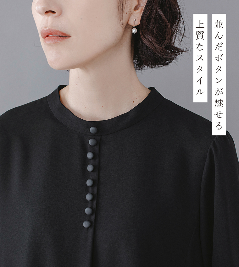 Luuna miu【慶弔両用】大切な日のボタンフレアワンピースのディテールイメージ。黒のワンピースの胸元をアップで写し、縦に並んだくるみボタンの上質な質感が際立つ。モデルはパールのピアスを着用し、右側には「並んだボタンが魅せる 上質なスタイル」という日本語テキストが添えられた商品画像。