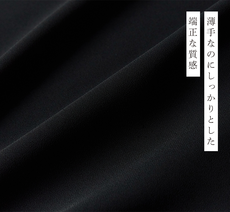Luuna miu【慶弔両用】大切な日のボウタイAラインワンピースの生地アップ。黒の布地をクローズアップし、薄手ながらしっかりとした質感と端正な表面の美しさが伝わる。右側には「薄手なのにしっかりとした 端正な質感」という日本語テキストが添えられた商品画像。