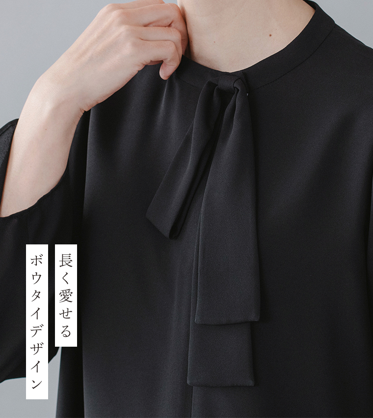 Luuna miu【慶弔両用】大切な日のボウタイAラインワンピースのディテールイメージ。黒のワンピースの首元をクローズアップし、軽やかに結ばれたボウタイが上品に揺れる。左側には「長く愛せる ボウタイデザイン」という日本語テキストが添えられ、シンプルながらも洗練された印象を与える商品画像。