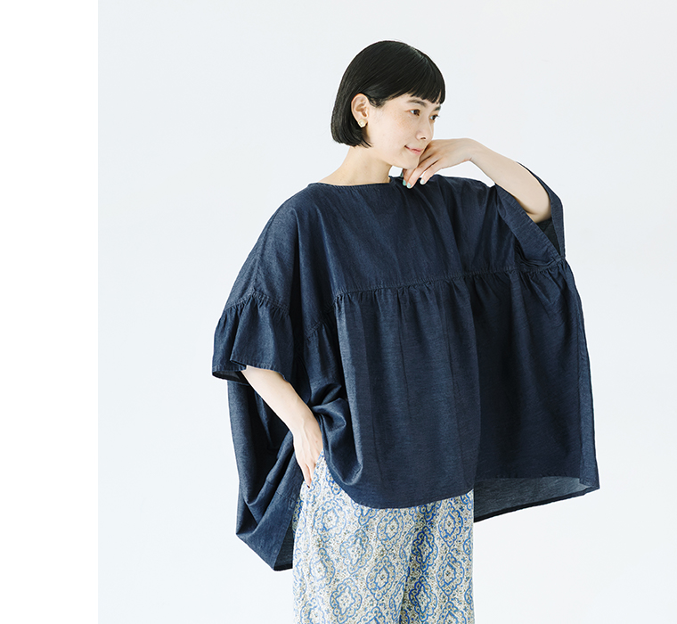 Sorte cuffぜいたくギャザーワイドブラウス（インディゴ）を着用した女性の横向きコーディネート。ふんわりと広がるギャザーとゆったりとした袖のデザインが特徴で、軽やかな素材感が際立つ商品画像。