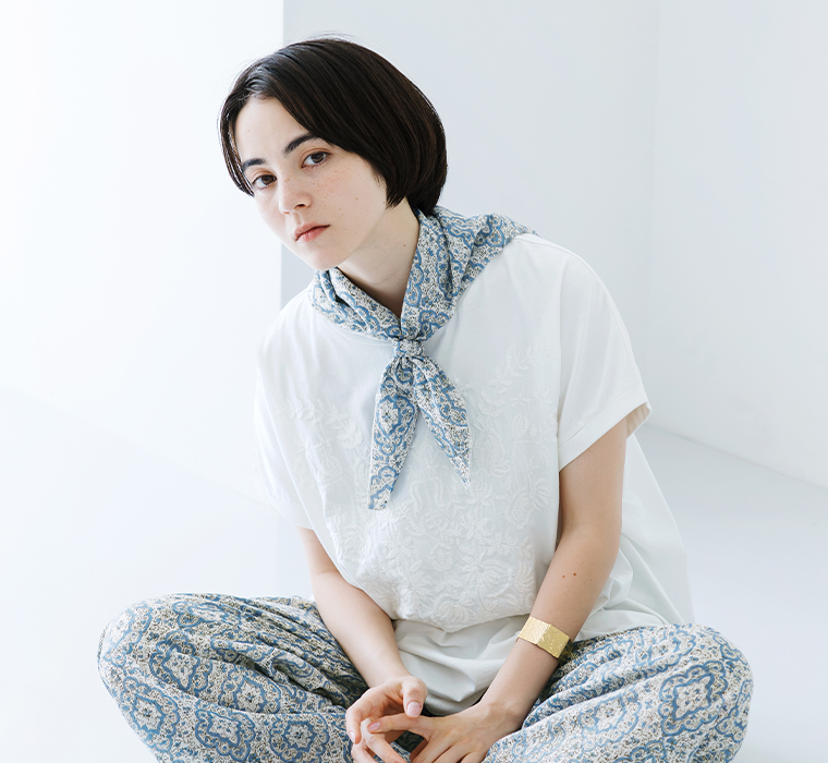 ボタニカル刺繍ワイドTシャツ(ホワイト)を着用しタイル総柄スカーフを首元に巻いて座ったカット
