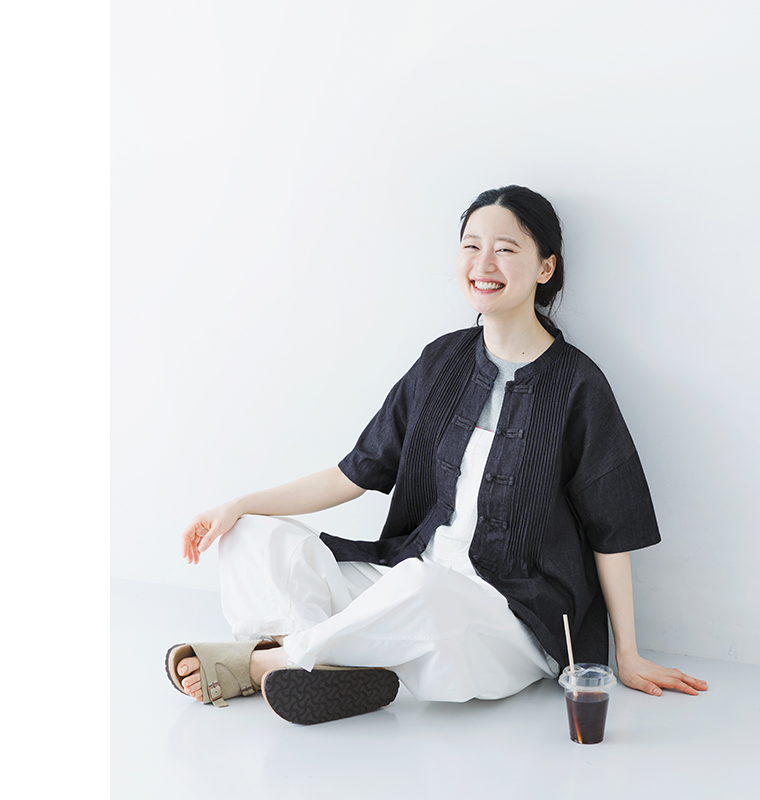 コットンデニムチャイナボタンブラウスネイビーを着用したモデルが座っている画像
