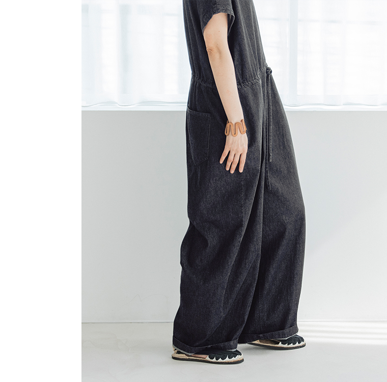 &yarn 滝口和代さんコラボ　or frill all in oneのサイドシルエット。黒のオールインワンのゆったりとしたラインが自然に流れ、ポケット位置やタックの立体感が際立つデザイン。素材の柔らかさと動きのあるシルエットを表現した横向きの着用イメージ。