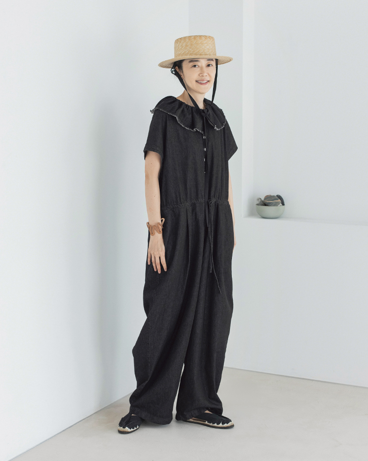 &yarn 滝口和代さんコラボ　or frill all in oneを着用したイメージ。黒のフリル付きオールインワンに麦わら帽子を合わせたスタイル。軽やかな素材感とナチュラルな雰囲気が調和し、夏らしい上品な印象を演出する商品画像。