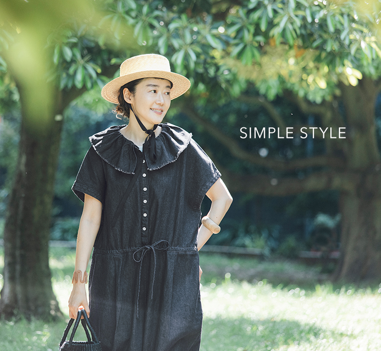 田中帽子店 滝口和代さん×田中帽子店コラボ quiet straw hat の着用イメージ。黒いリボン付きの麦わら帽子をかぶった人物が、黒のワンピースを合わせて屋外で微笑む姿。木漏れ日の中で「SIMPLE STYLE」の文字が添えられた、ナチュラルで穏やかな雰囲気のスタイリングカット。