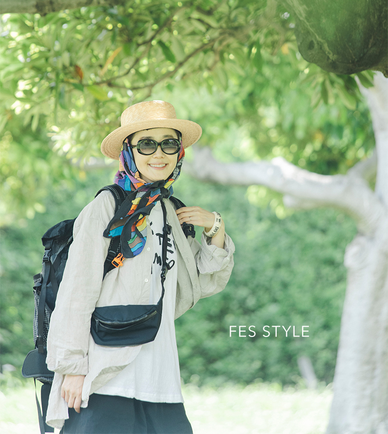 田中帽子店 滝口和代さん×田中帽子店コラボ quiet straw hat の着用イメージ。麦わら帽子にカラフルなスカーフを合わせ、サングラスとリネンシャツを着た人物が屋外で微笑む姿。「FES STYLE」の文字入りで、軽やかで遊び心のあるフェススタイルを表現したカット。