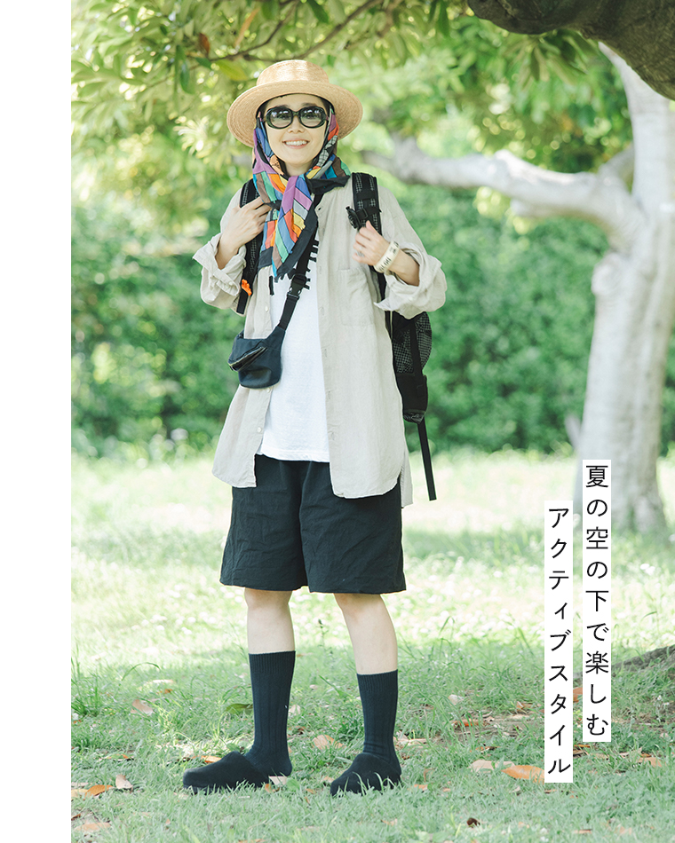 田中帽子店 滝口和代さん×田中帽子店コラボ quiet straw hat の着用イメージ。麦わら帽子にカラフルなスカーフを合わせ、サングラスとリネンシャツ、黒のショートパンツを着た人物が屋外で微笑む姿。「夏の空の下で楽しむ アクティブスタイル」の文字入りで、軽快でフェス感のあるスタイリングを表現したカット。