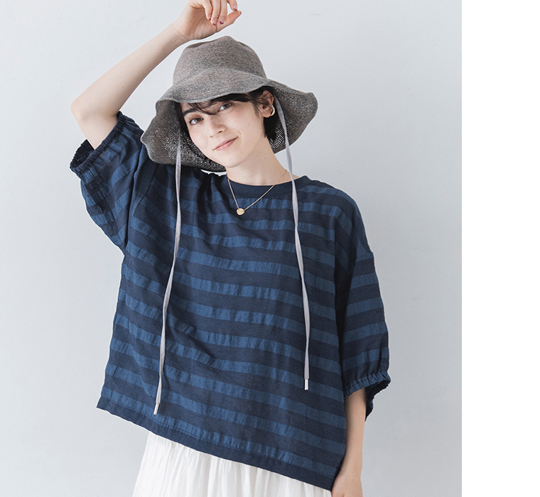 SUN VALLEYテンセルシアーボーダーリブ付きブラウス（ネイビー）にストローハットと白のボトムスを合わせた正面コーディネート画像
