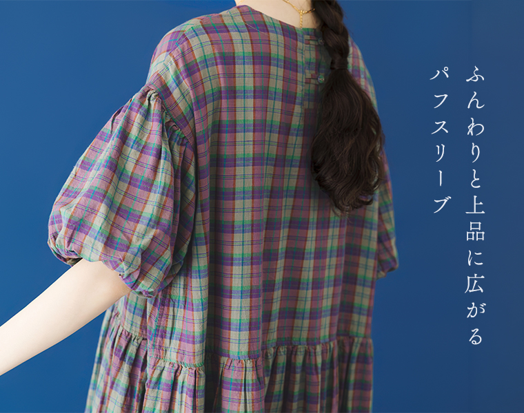 Lintu Lauluマドラスチェックワンピース（パープル系）のパフスリーブとバックスタイル。青い背景で、後ろを向いた女性の首元から背中、袖にかけてのアップカット。「ふんわりと上品に広がるパフスリーブ」の文字が添えられている