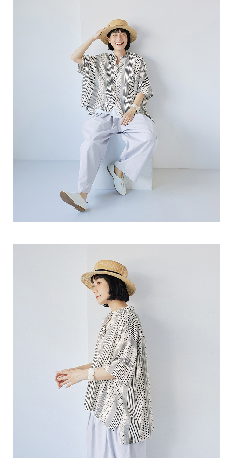 ベージュのパッチワークプリントブラウスと淡いパンツを合わせた女性モデルの座りスタイル