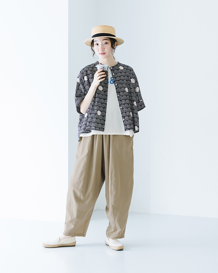 CALINERライトボイルLINE DOTプリント ワイドシャツ（ブラック系）を羽織りとして着用し、ロゴTシャツとベージュのバルーンパンツに合わせたコーディネートの着用画像