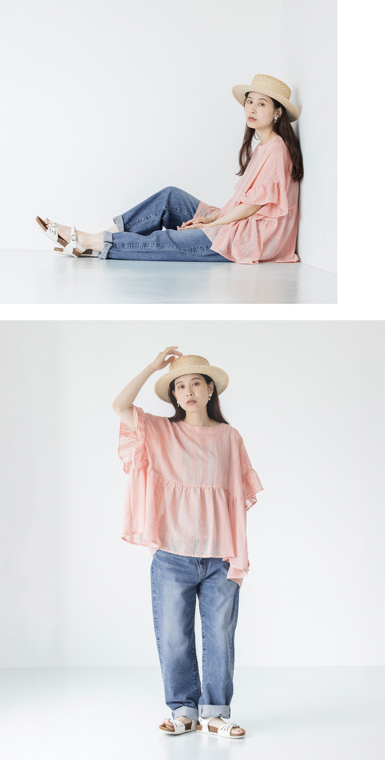 ピンクのシアー刺繍プルオーバーにデニムを合わせた女性モデルの全身スタイル