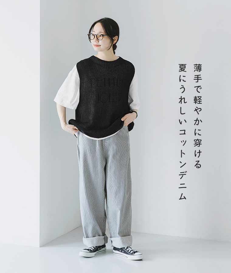 コットンデニム脚長パンツを白いTシャツと黒のニットベストに合わせ、裾をロールアップした全身コーディネート画像
