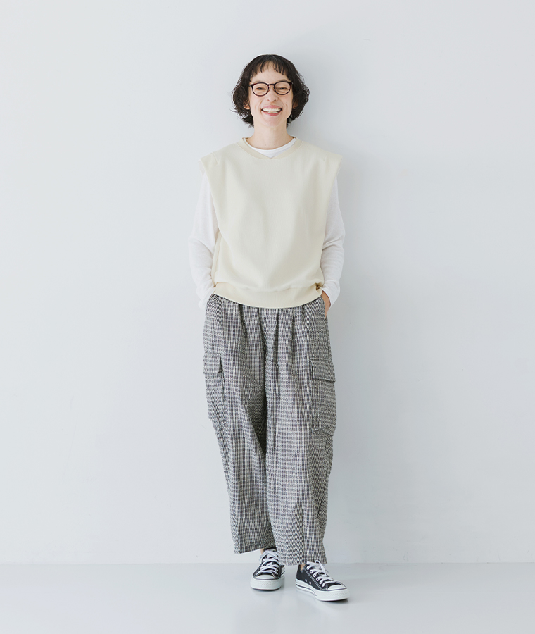 リップルチェックカーゴイージーパンツにアイボリーのベストと白いプルオーバーを合わせた女性モデルの全身スタイル