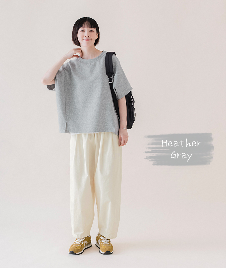 杢グレーのカットベストを白のパンツとスニーカーに合わせ、黒のリュックを背負った全身コーディネート画像