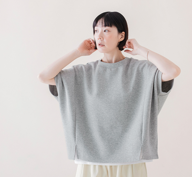 杢グレーのカットベストのゆったりとした身幅と、腕まわりを包むワイドなシルエットがわかる正面の着用画像