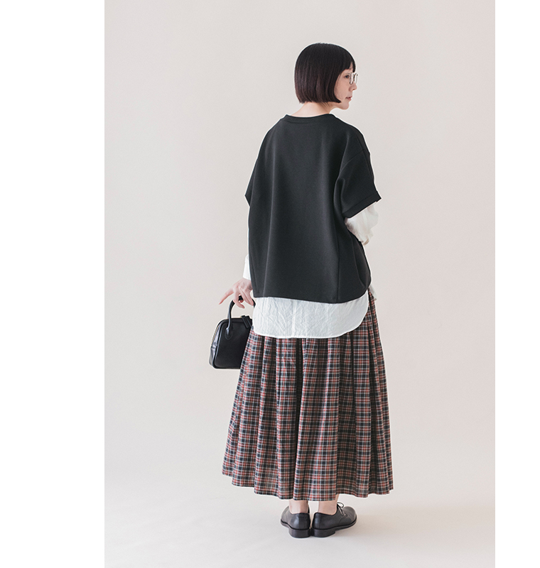 ブラックのカットベストのゆったりとした後ろ姿と、白シャツとのレイヤードがわかるバックスタイル画像