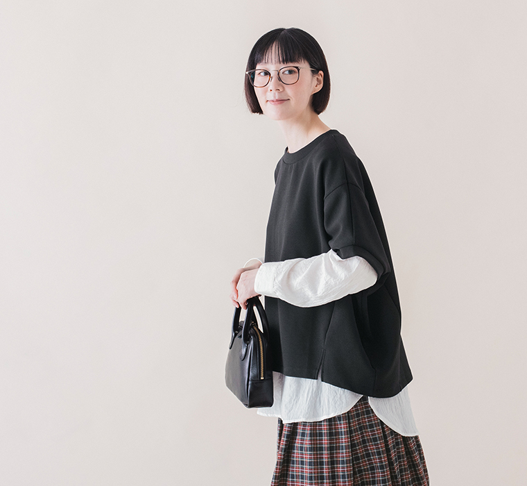 ブラックのカットベストのサイドスリットとゆったりとしたシルエットがわかる横向きの着用画像