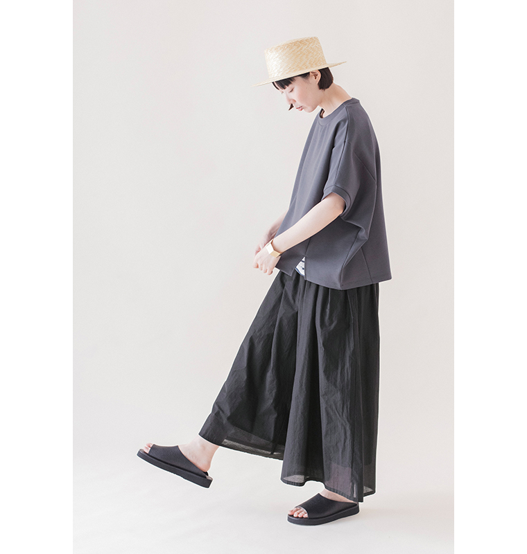 ナスコンのカットベストに黒のロングスカートを合わせた、ゆったりとしたシルエットがわかる横向きの着用画像