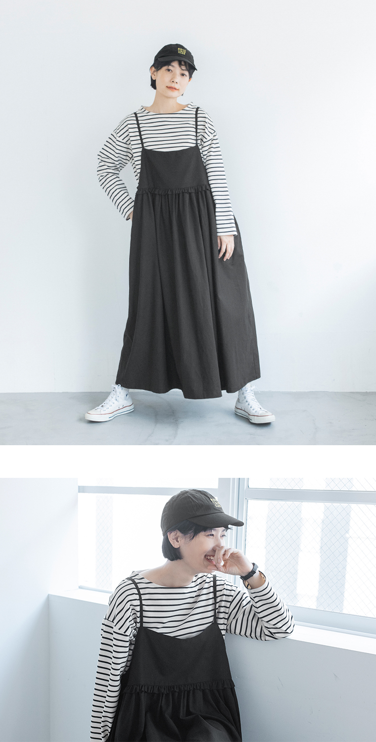 ブラックのジャンパースカートにボーダーの長袖Tシャツと白スニーカーを合わせた女性モデルのカジュアルスタイル