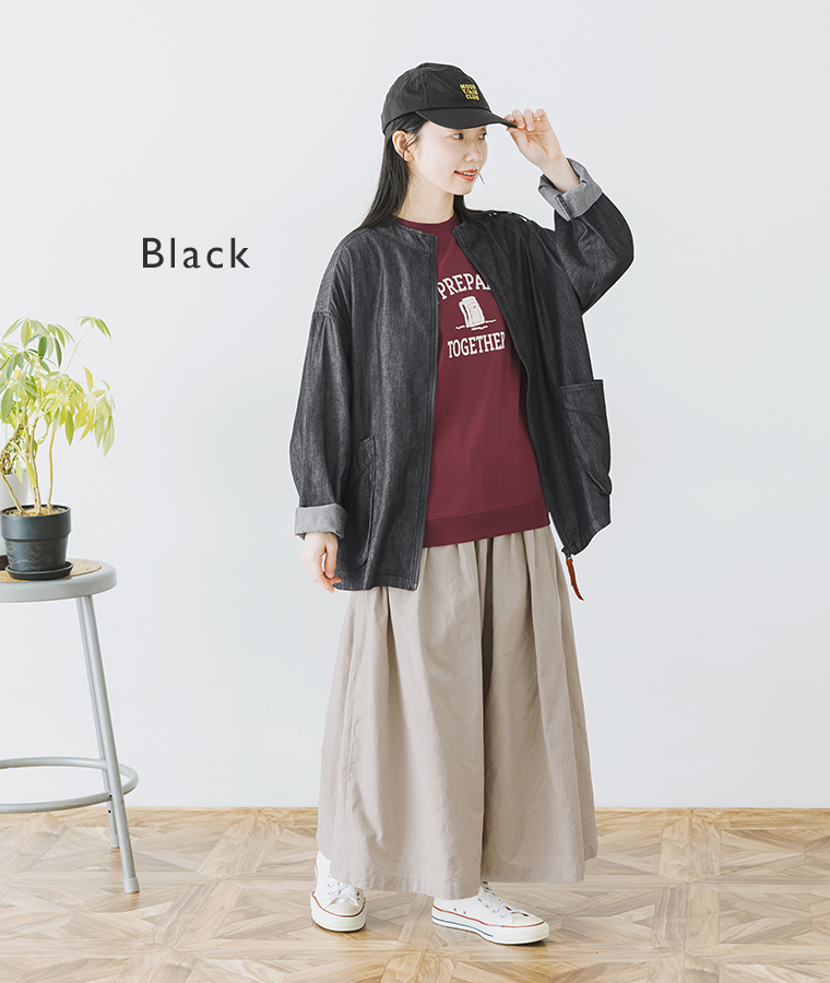 ブラックのスタンドカラージャケットを羽織った、赤のプリントトップスとベージュスカートの全身コーディネート画像