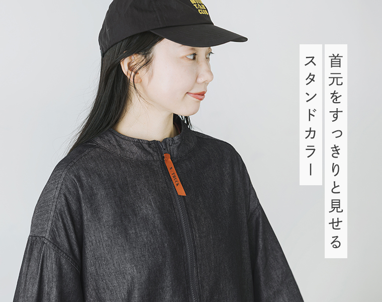 ブラックのスタンドカラージャケットのすっきりとした首元とアクセントになるオレンジのファスナー引き手を見せた上半身画像