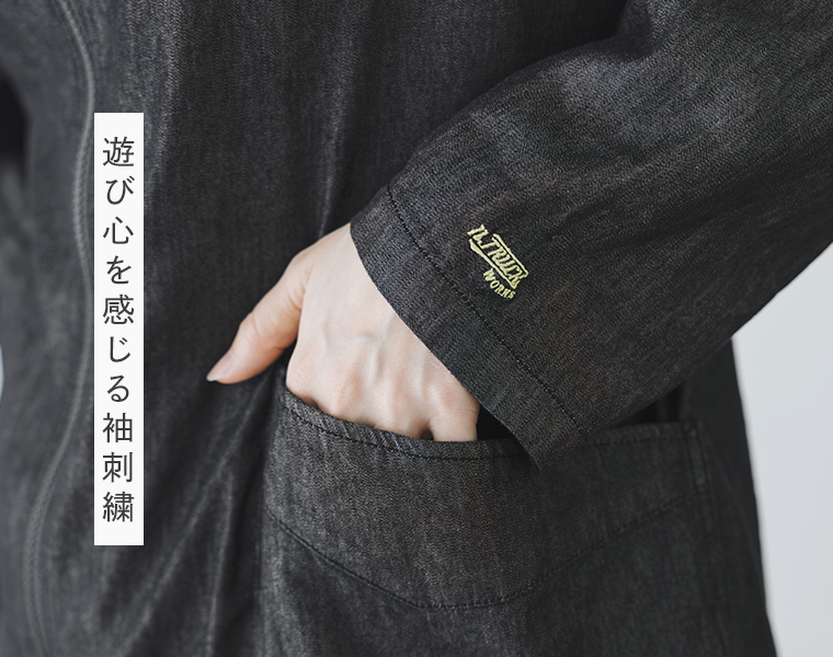ブラックのスタンドカラージャケットの袖口に施したワンポイント刺繍とフロントポケットのディテール画像