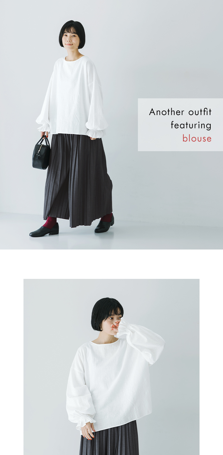 白ブラウスとグレーのプリーツパンツを合わせた女性モデルのコーディネート