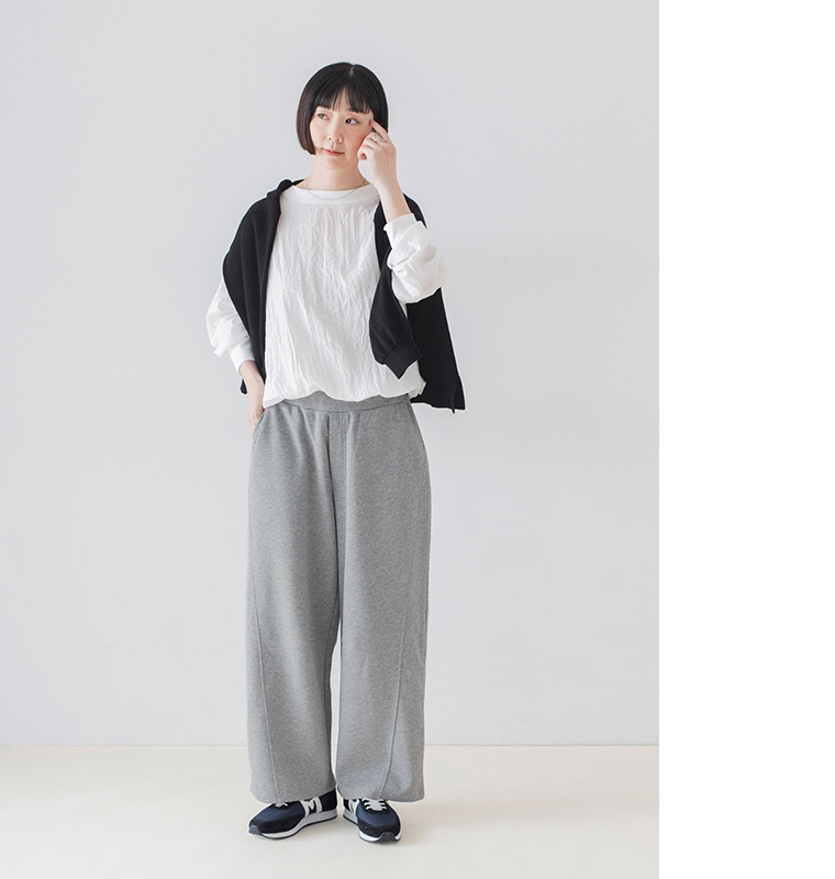 杢グレーのこなれスウェットカーブパンツに白いブラウスと黒の肩掛けニットを合わせた全身コーディネート