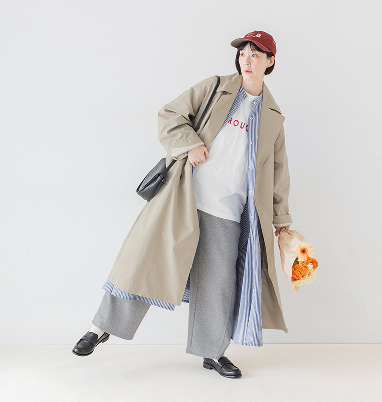 杢グレーのこなれスウェットカーブパンツにベージュのロングコートとストライプシャツを重ねた着用画像