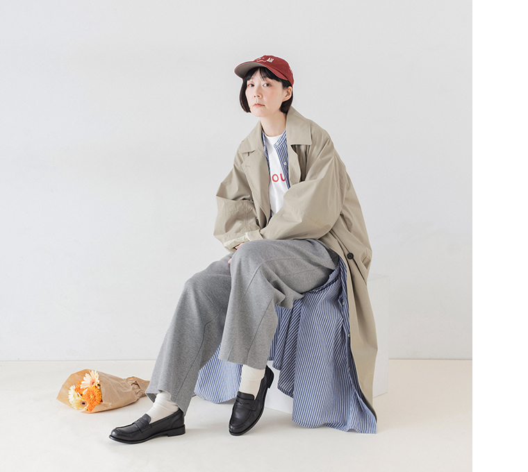 杢グレーのこなれスウェットカーブパンツにベージュのロングコートを合わせた座り姿のコーディネート