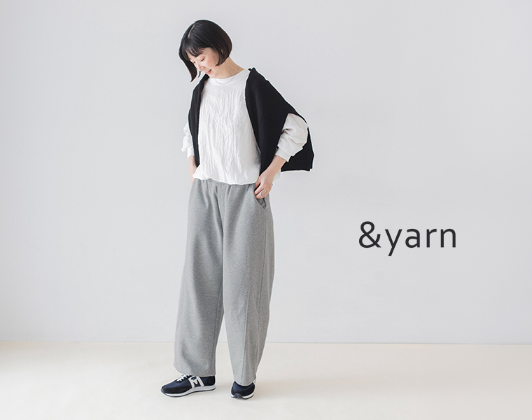 &yarnの杢グレーのこなれスウェットカーブパンツに白いブラウスと黒の肩掛けニットを合わせた全身コーディネート