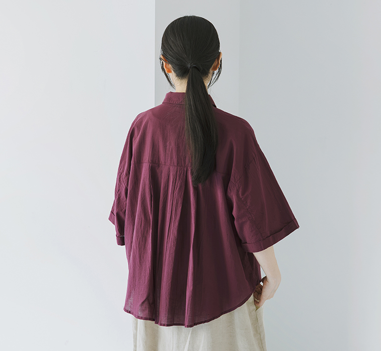 キャンブリック ボタニカル刺繍シャツの背面タックとゆったりとしたシルエットがわかる後ろ姿