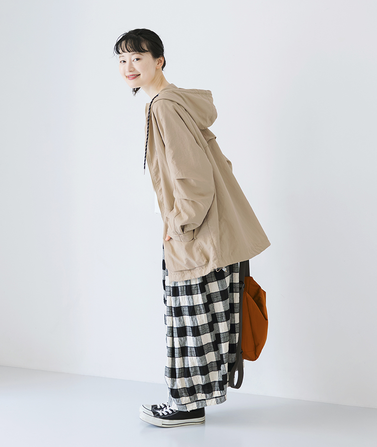 ベージュのシャカシャカミドルフードジャケットにチェック柄パンツを合わせた横向きの着用カット