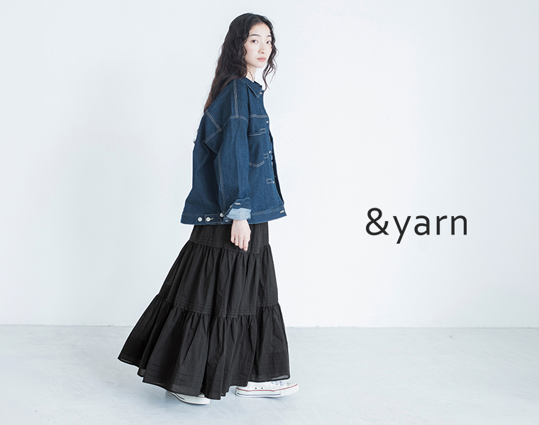 &yarnのブラックのタックティアードロングスカートにデニムジャケットとスニーカーを合わせた横向きの着用カット