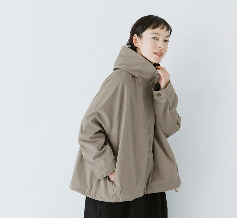 グレーベージュのフードZIPジャケットを着用し、立体的なフードとゆったりとしたシルエットを見せたモデルの上半身カット