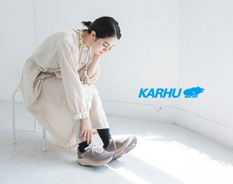 KARHUのグレーのスニーカーを履き、靴ひもに手を添える女性モデル
