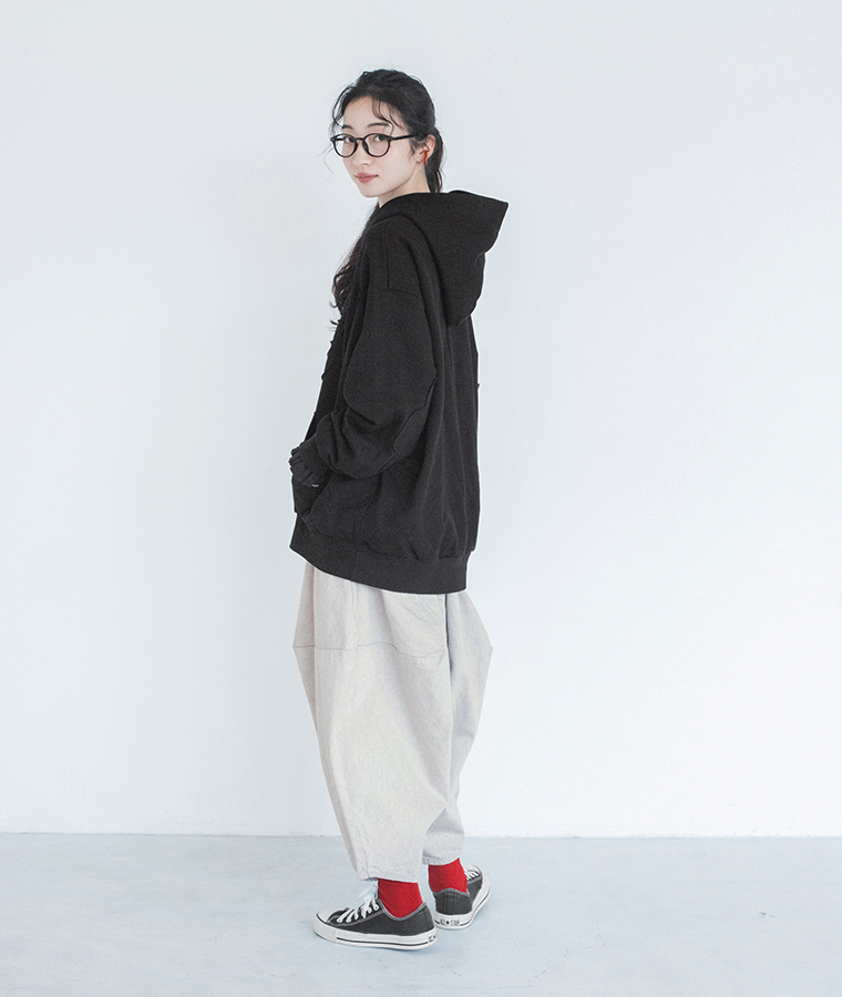 コットン白黒デニムポインテッドデニムパンツを黒のフードプルオーバーとスニーカーに合わせたバックスタイル