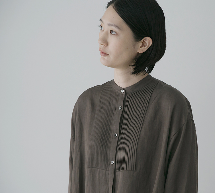 ブラウンのロングシャツの襟元と胸元のピンタック
