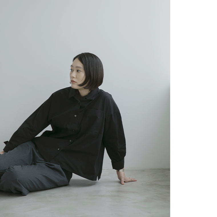 ブラックのタイプライターシャツを着用して床に座る女性モデル