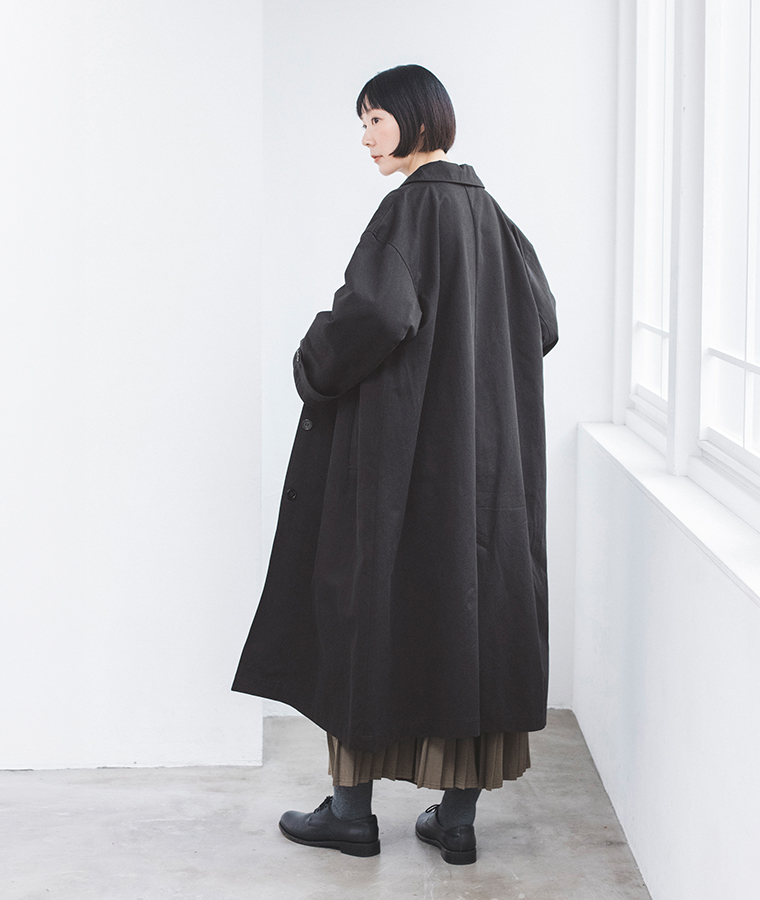 ブラックのわたしの定番ステンカラーコートのゆったりとしたシルエットと後ろ姿を見せた着用カット
