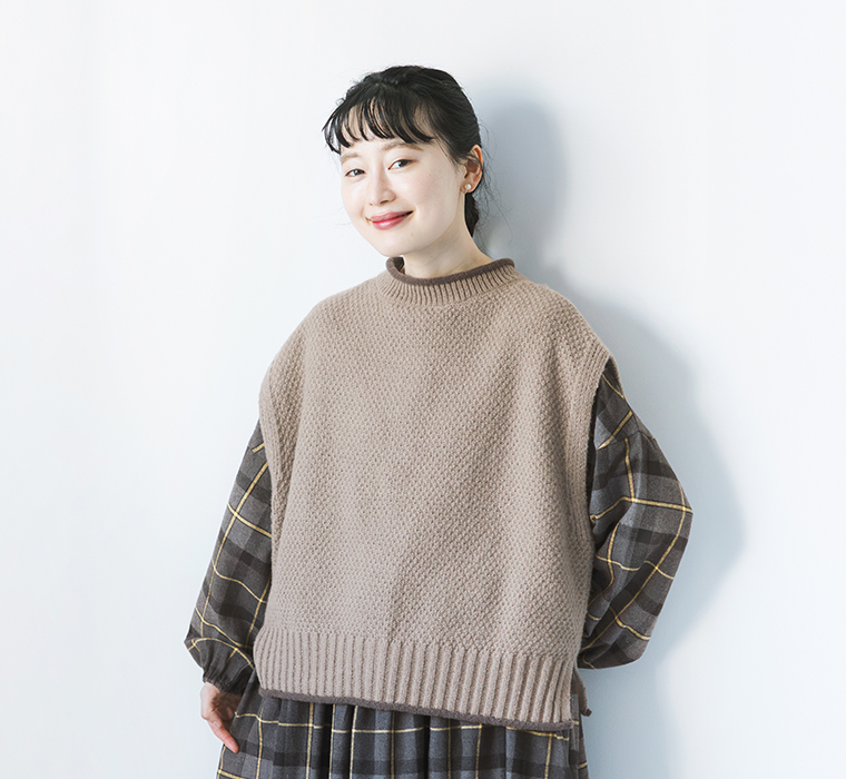amitieのブローくるん配色デザイン2wayベストをチェック柄ワンピースに重ねたモデルの正面上半身カット