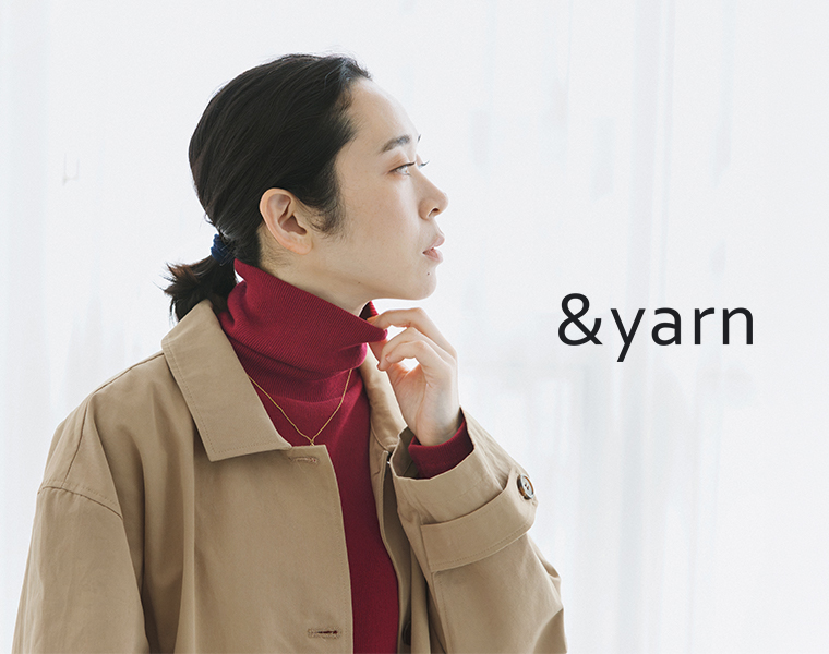 &yarnの「わたしの定番タートルネック」を着用し、ベージュのコートを重ねた女性モデル