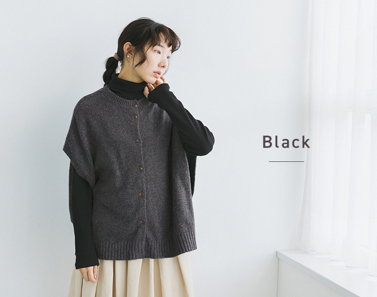 ブラックのタートルネックにグレーのニットベストを重ねた女性モデル