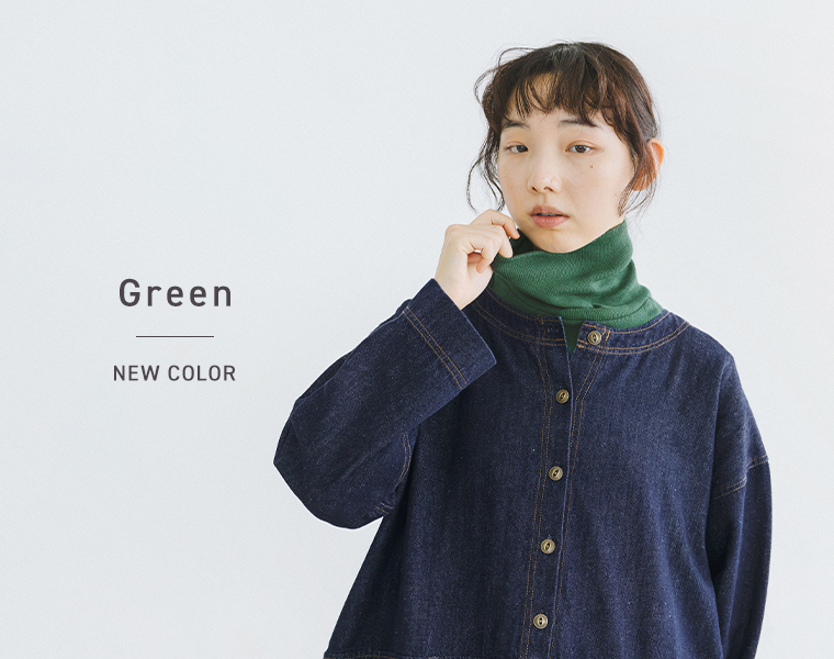 グリーンのタートルネックにデニムワンピースを重ねた女性モデル