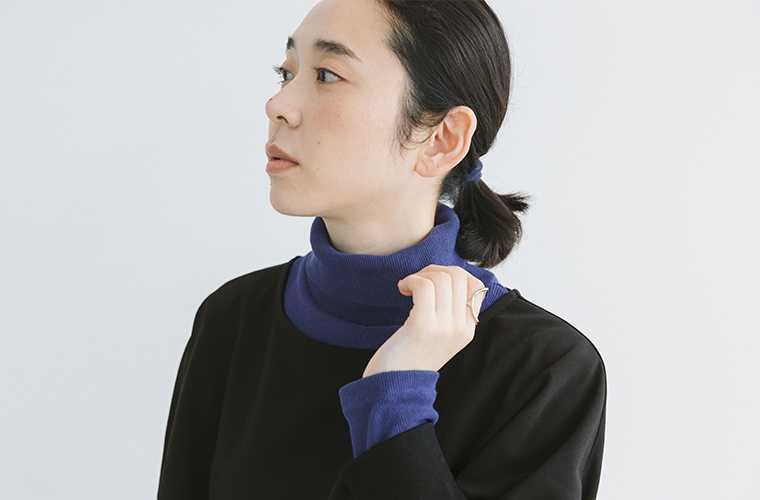 黒のプルオーバーからのぞくブルーのタートルネックの首元と袖口