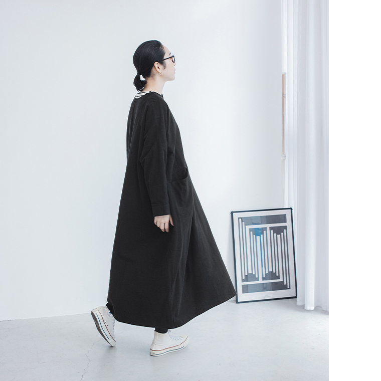 ブラックのコクーンワンピースを着用した女性モデルの横向きのスタイル