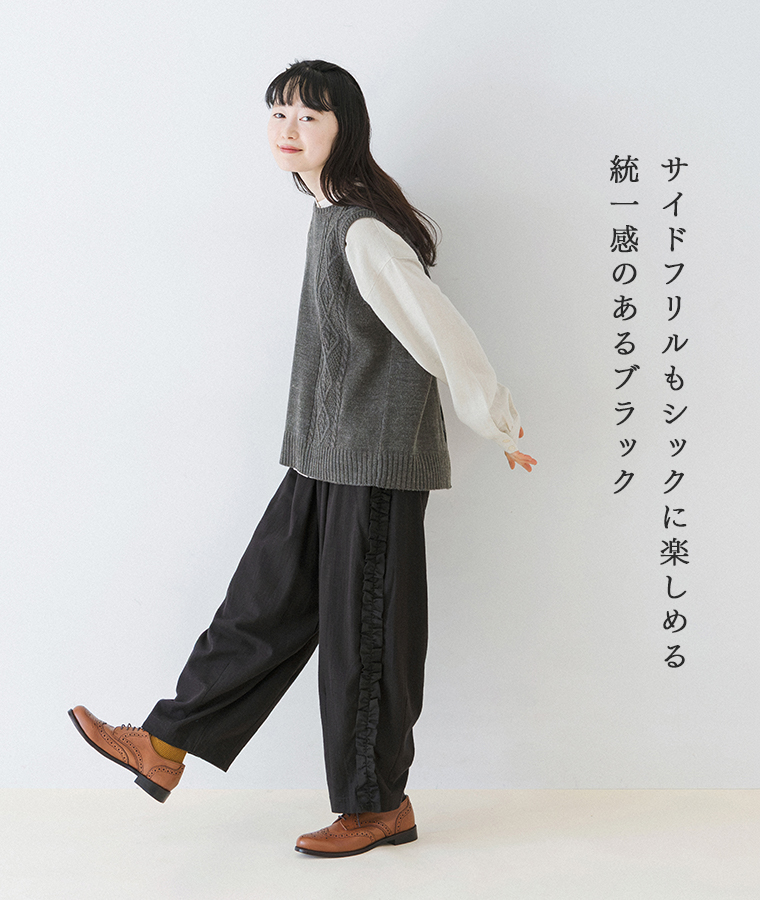 表起毛コットンリネンヘリンボーンサイドフリルパンツをグレーのニットベストと合わせたモデルの横向き全身コーディネート
