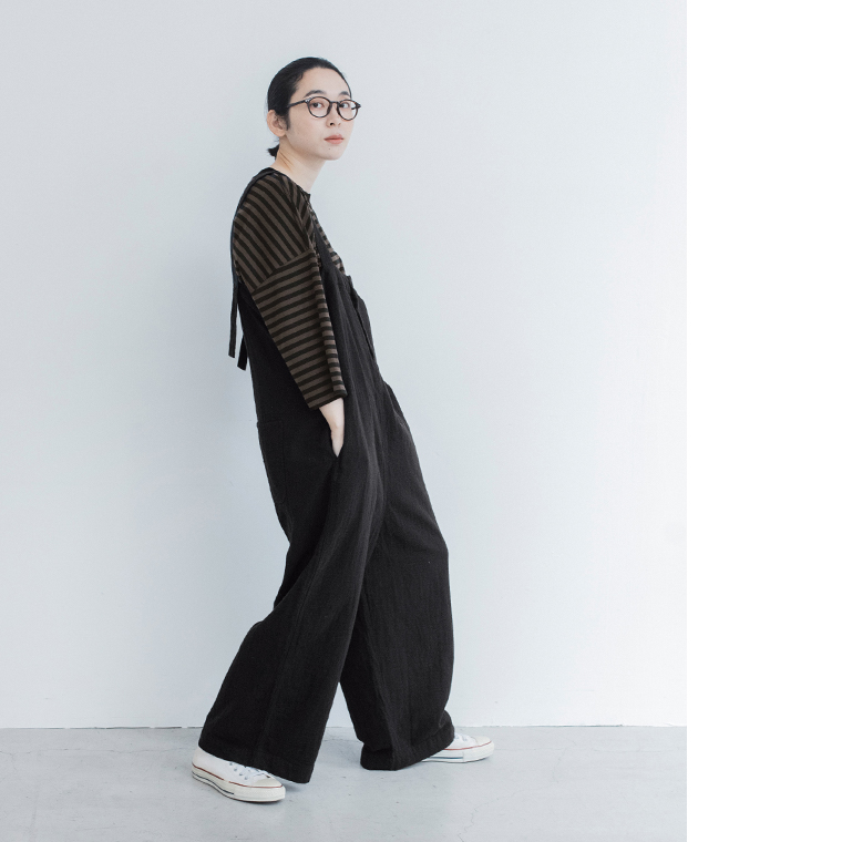 ブラックのサロペットのゆったりとしたシルエットがわかる横向きの着用姿